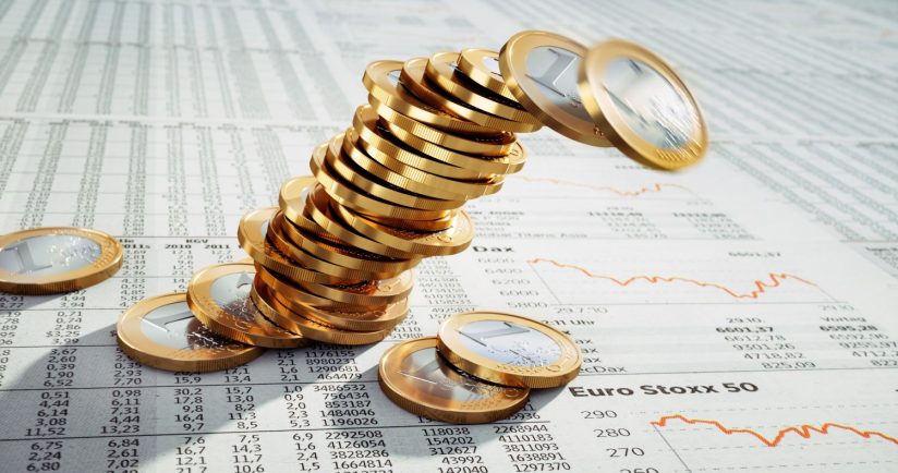 Ein Stapel Euro-Münzen fällt auf ein Finanzdokument mit Diagrammen und Zahlen.