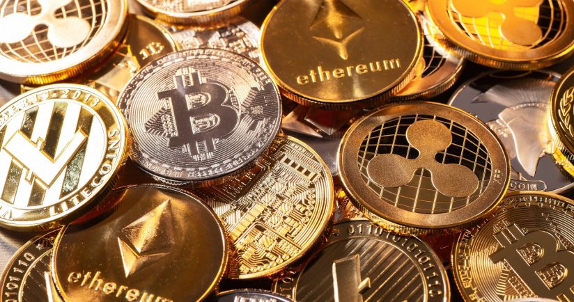 Verschiedene physische Münzen mit Kryptowährungslogos wie Bitcoin und Ethereum.