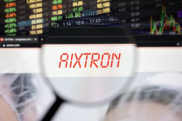 Vergrößerte Ansicht eines Monitors mit der roten Aufschrift "AIXTRON" und Börsenkursen im Hintergrund.