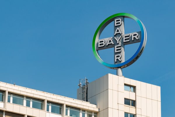 Auf dem Bild ist ein Gebäude mit einem großen, kreisförmigen Bayer-Logo auf dem Dach zu sehen.