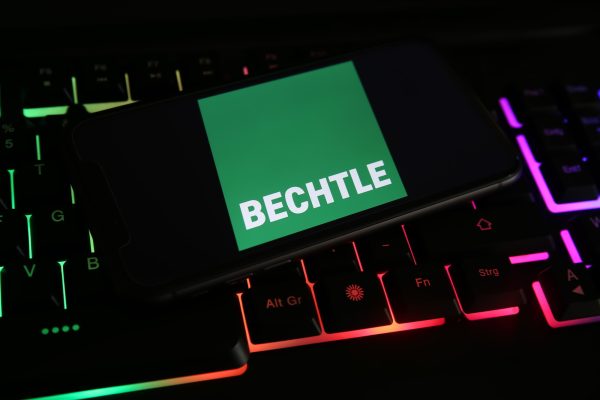 Smartphone mit grünem Bechtle-Logo auf bunter Tastatur.