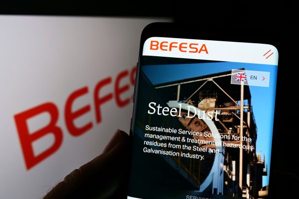 Smartphone-Bildschirm zeigt eine Webseite mit dem Titel "Steel Dust" und einem Industriegebäude.