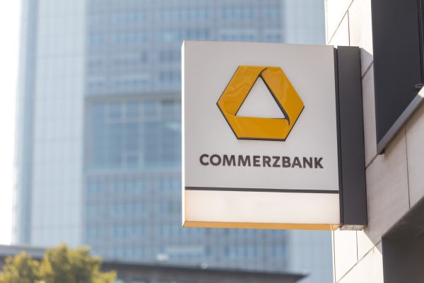 Das Commerzbank-Logo auf einem Schild vor einem modernen Bürogebäude.