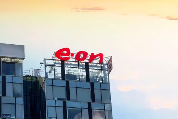 Hochhaus mit großem, roten Logo auf dem Dach. Hintergrund ist ein heller, strukturierter Himmel.