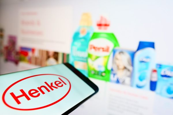 Tablet mit Henkel-Logo vor unscharfen Drogerieprodukten im Hintergrund.