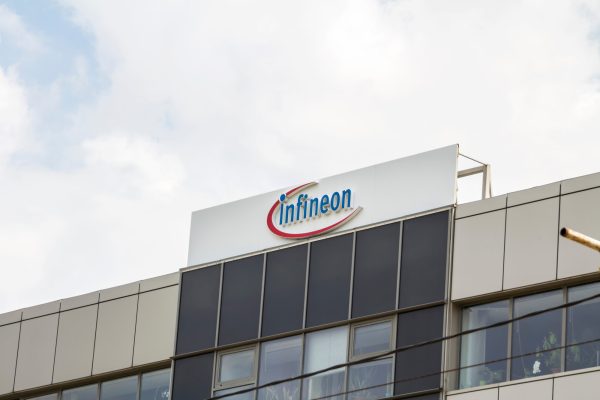 Gebäude mit Infineon-Logo auf dem Dach bei bewölktem Himmel.